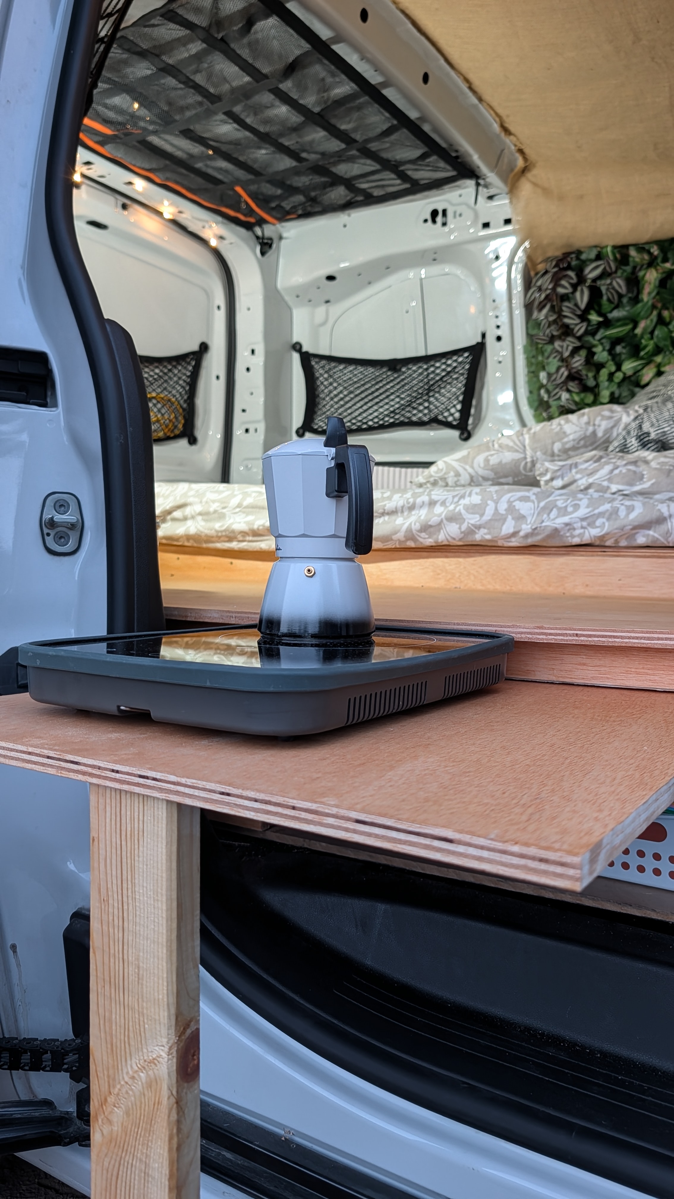 Cocina de inducción portátil sobre la mesa de madera de la furgoneta
